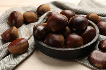 Sweet fresh edible chestnuts on light wooden table, closeup