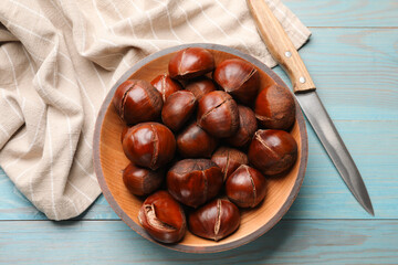 Fresh edible sweet chestnuts and knife on light blue wooden table, flat lay