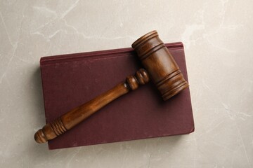 Wooden gavel and book on light textured table, top view