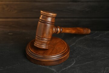 Wooden gavel on dark textured table, closeup