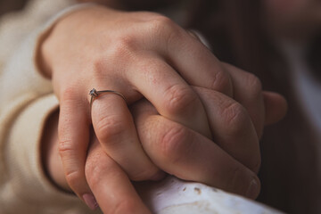 Manos de una pareja romántica sosteniéndose con fuerza y mostrando un delicado anillo con una...