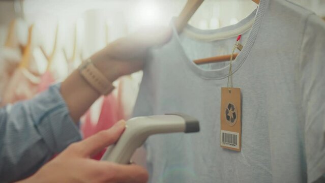 The manager of a shopping center uses modern scanning technology, using a laser scanner with a red laser beam to account for goods. An Asian worker scans barcode labels on product tags