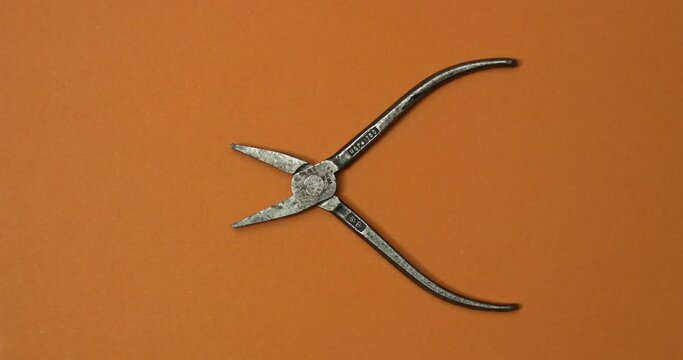 Pliers in action on color background. Loopable stop motion animation. 4K top view. DIY video concept.