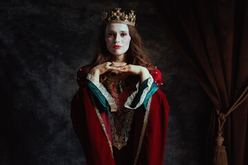 medieval queen in red dress with white makeup and crown