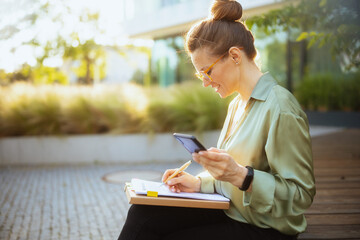 happy woman worker in green blouse and eyeglasses using phone