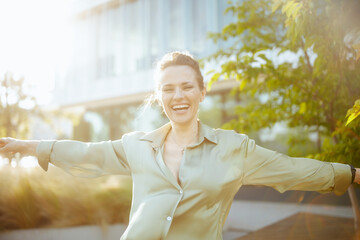 smiling modern woman worker near office building rejoicing