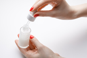 girl uses with a bottle of serum. Close-up of women's hands. Presentation of a cosmetic product.
