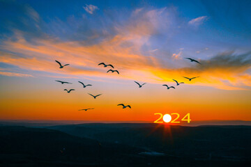 Transition from 2023 to new year 2024 concept with text on sun rising sky. Life is short birds are flying.