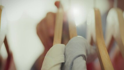 There is a sale going on in a bright store, a stylish woman in stylish clothes carefully examines the goods on the hangers. A modern girl follows fashion trends and trends, showcases a modern boutique