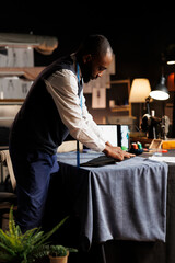 Expert suitmaker meticulously working on suit blazer in atelier shop workspace with precision and...