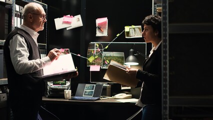Law agents read witness statements to connect the dots in solving criminal case, using classified documents to find the missing puzzle piece. Professional investigators clandestine operation.