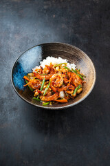 Traditional Thai fried king prawns with vegetable, cashew nuts and rice served as close-up in a design plate with text space