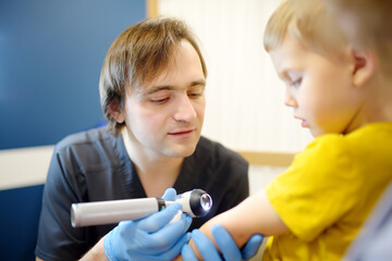 A caring doctor checks moles on the skin of a small child. A dermatologist doctor looks at a rash...