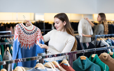 Young woman looking for casual sweater for cold days in showroom, having shopping day, find something on sale