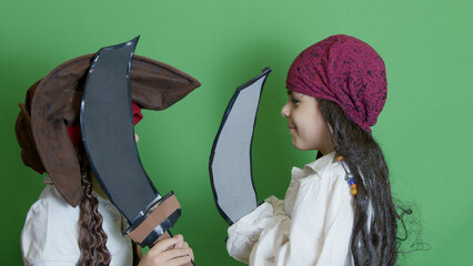Pirates fight with cutlasses. Cute brothers dressed as pirates playing isolated on green...