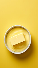 Bowl with melting butter or cheese on yellow background, top view, copy space. Dairy products