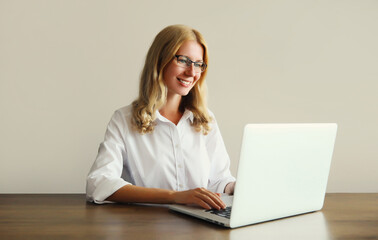 Happy woman working with laptop sitting at desk in office or home