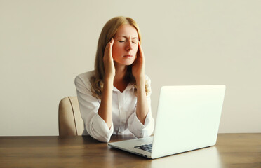 Tired overworked woman employee suffering from headache, migraine, working with laptop in office