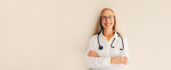 Portrait of happy friendly smiling middle-aged woman doctor with stethoscope and crossed arms