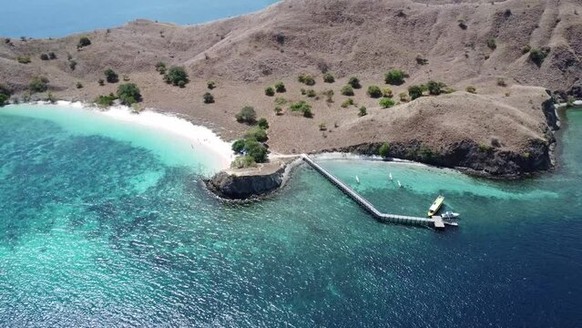 View from above. Pink beach tourist destination in Labuan Bajo, Lombok, Indonesia, Asia. Beautiful mountains and beaches, there is a harbor bridge and small boats.