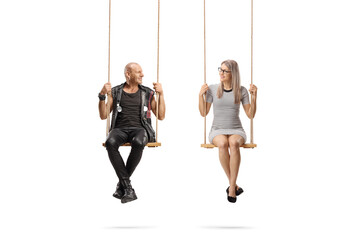 Punk sitting on a swing and looking at a young woman