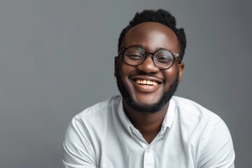 Obraz premium Smiling African American man wearing glasses laughing and posing for a picture isolated on a grey background