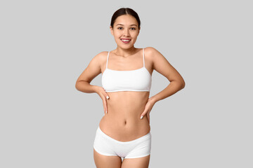 Fototapeta premium Slim young woman in underwear on light background. Weight loss concept