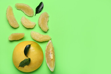 Fresh pomelo fruit, slices and leaves on green background
