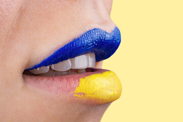 Close up of beautiful and plump female lips painted in blue and yellow. Lips of woman painted in Ukrainian flag colors.