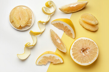 Cut sweet pomelo, plate with slices and peel on colorful background
