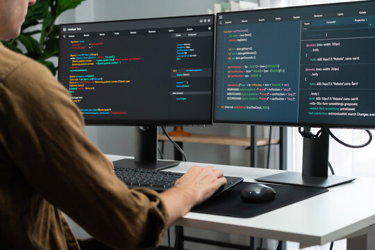 IT developer working online software development on pc monitors at modern home office on coding application screens, creating updated latest program firmware information version concept. Gusher.