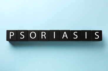 Word Psoriasis made of black wooden cubes with letters on light blue background, top view