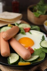 Delicious breakfast with boiled sausages and fried egg on wooden table, closeup