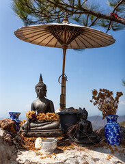 Buddha image under umbrella on the slope of Doi Nangmo mountain near Chiang Mai, Northern Thailand.