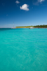 Seascape with crystal clear shallow turquoise ocean water, deep blue sky and white yachts and boats on the water surface. Saona Island, Dominican Republic. Wide angle shot.