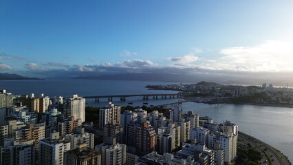 Bela imagem a&eacute;rea das pontes de acesso a Florian&oacute;polis ao entardecer com o mar ao fundo.