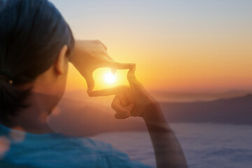 Close up of hands making frame gesture with sunset, Female hand capturing the sunrise. Planning and vision concept