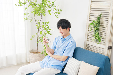 リビングでスマートフォンで動画を見る男性