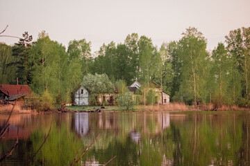 Obraz premium An old wooden house in the forest on the shore of a lake. Village landscape