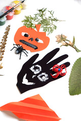 Child making for the holiday of Halloween. Funny crafts from paper and natural dry plants. Halloween decor. DIY.