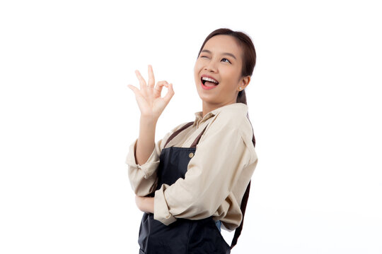 Portrait smiling young asian woman wearing apron showing ok sign with hand isolated white background, young asian woman making okay gesture, waitress or entrepreneur, small business or startup.