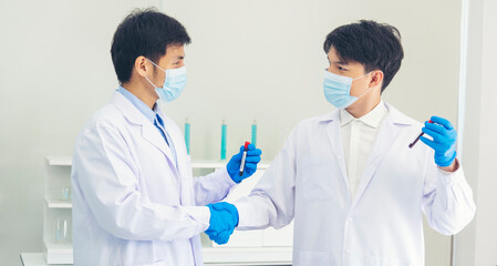 Two asian scientist men team partner shake hands together. Men researcher holding chemistry science tube experiment biotech antibody sample in laboratory. Close up hand corporate coworker partnership