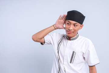Young Asian moslem man put hand near ear try to listening sound or secret news