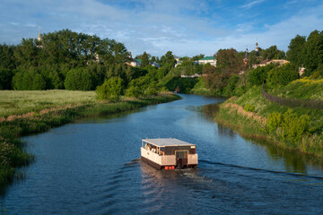 View of the Kamenka River flowing through the ancient city of the Golden Ring of Russia, Suzdal, and a floating river tram, Suzdal, Vladimir region, Russia