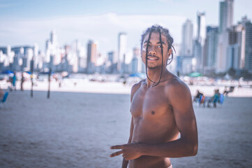 17-year-old Afro-descendant teenager with braids in his hair and no shirt, various facial expressions, city of Balneário Camboriu in the background is blurred
