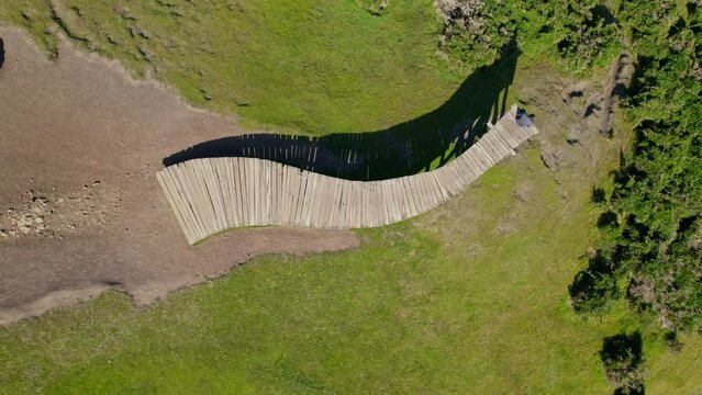 Rotating overhead view of the Muelle de las Almas with a person sitting meditating in solitude, Cucao Chiloe, Chile.