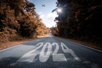 Word on strait road new year 2024 written on the road in the middle with forest along way beside...