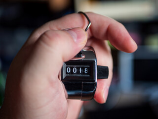 Hand Holding a Tally Counter Showing Number 18
