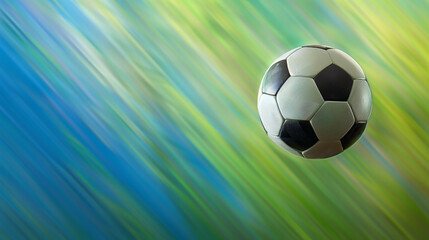 Naklejka premium Classic black and white soccer ball mid-air with a dynamic, streaked green and blue motion blur background - ideal for sports themes and copyspace