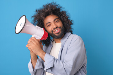 Young smiling attractive Arabian man promoter holds white megaphone in hands and looks at camera...